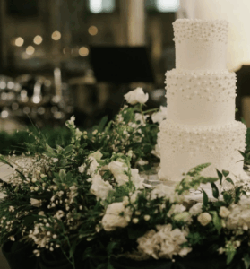 three-tiered white wedding cake surrounded by greenery